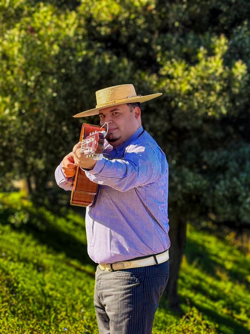 Pepe Flores con sombrero de paja y guitarra, al aire libre.