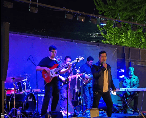 Chris-Ney canta junto a los músicos de Barnachea Project en el escenario de Panitao, con iluminación azul y violeta.